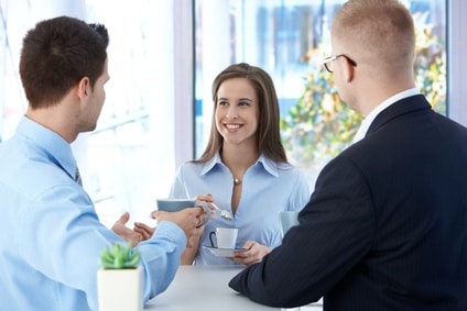 Coffee break in office, coworkers enjoying free time and conversation, smiling.